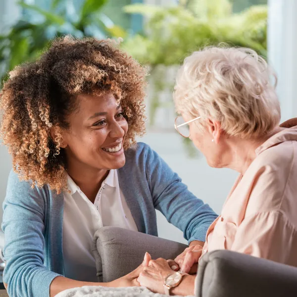 Une jeune femme et une dame âgée se sourient en se tenant les mains (photo d’illustration)