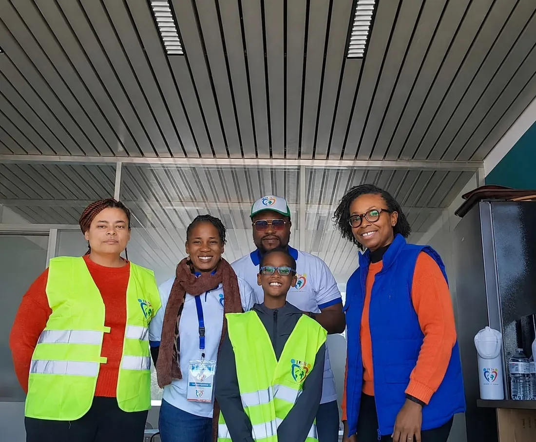 Cinq membres de l’équipe de La Joie du Cœur, dont un enfant, posent ensemble en souriant, en gilets et t-shirts de l’association