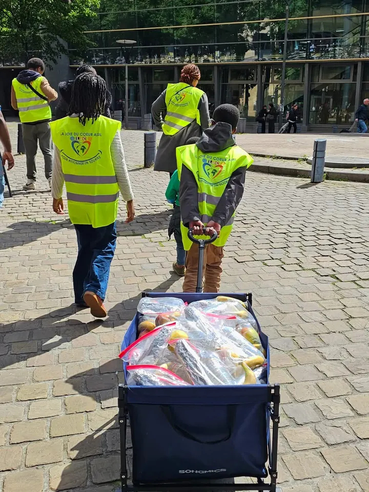 Bénévoles en gilet La Joie du Cœur tirant un chariot de provisions